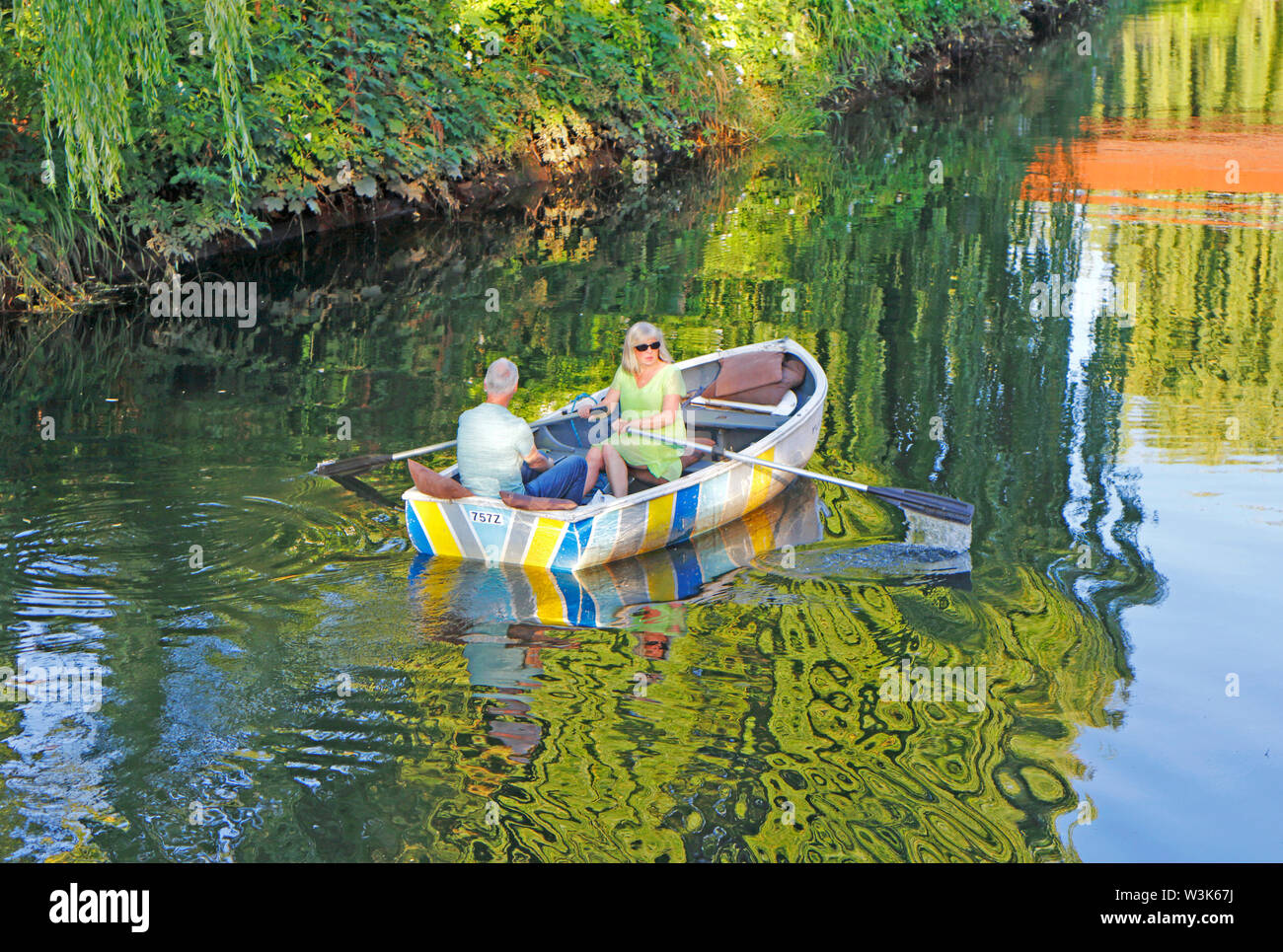 A couple in a rowing boat on a summer evening on the River Wensum in