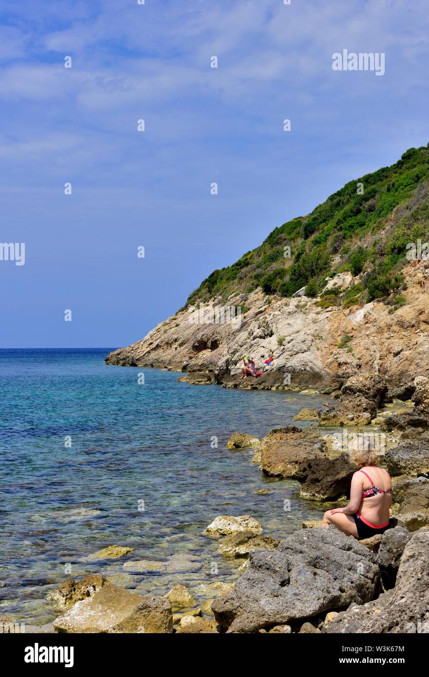A woman sitting on some rocks,Porto timoni, Cape Arillas, Afionas, Corfu, Greece,ionian islands Stock Photo
