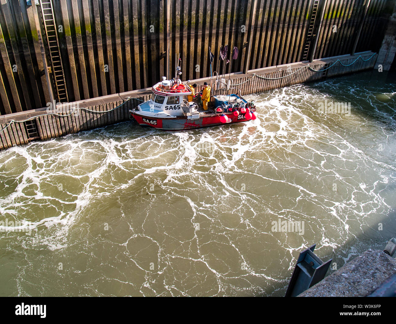 Tawe Barrage Lock in Swansea. A small fishing boat is in the lock as the lock is filled with water. Swansea marina, Wales, UK. Stock Photo