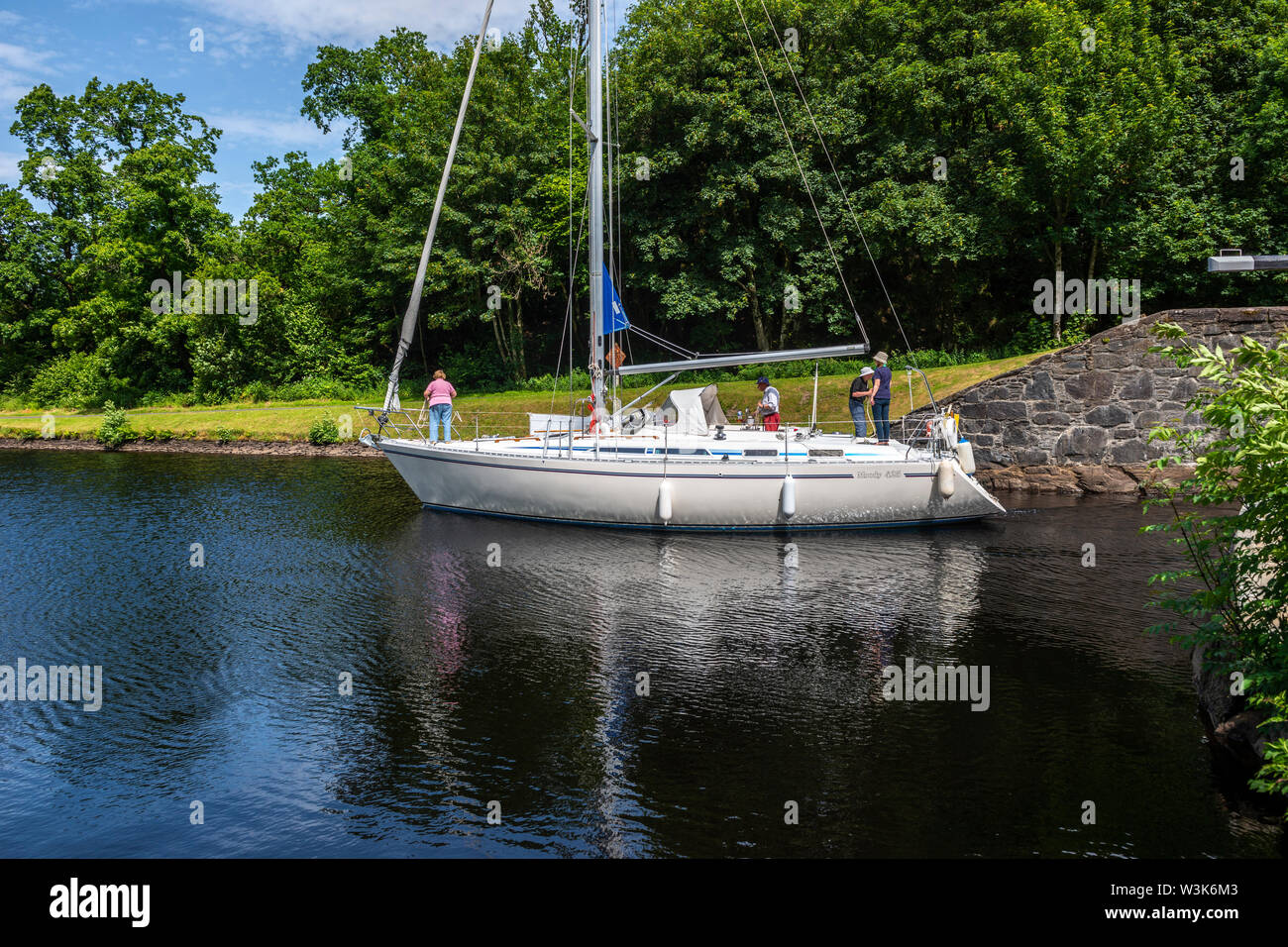Yacht exiting lock 10 and heading west towards Crinan - Dunardry on Crinan Canal, Argyll and Bute, Scotland, UK Stock Photo