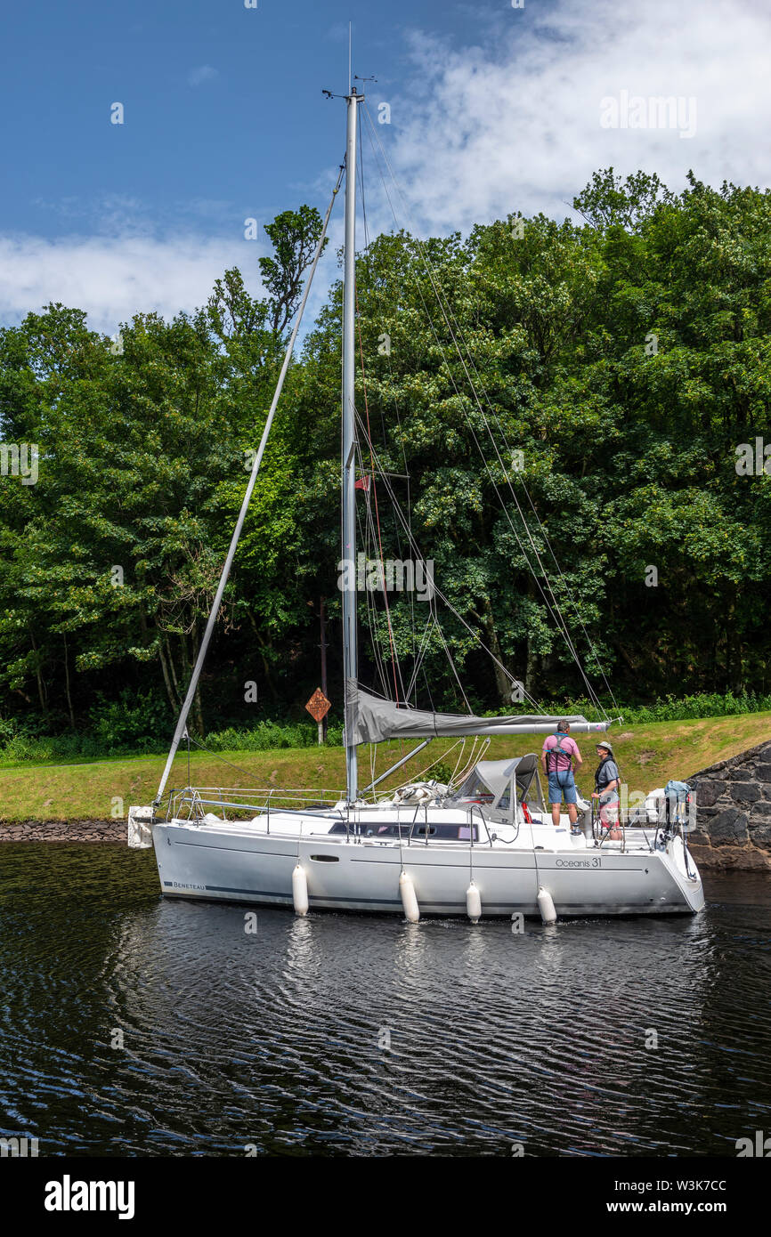 Yacht exiting lock 10 and heading west towards Crinan - Dunardry on Crinan Canal, Argyll and Bute, Scotland, UK Stock Photo