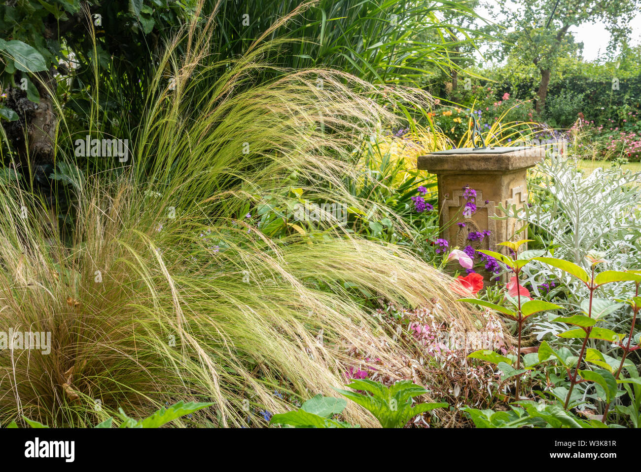 A sundial in amongst planting in a garden. Stock Photo
