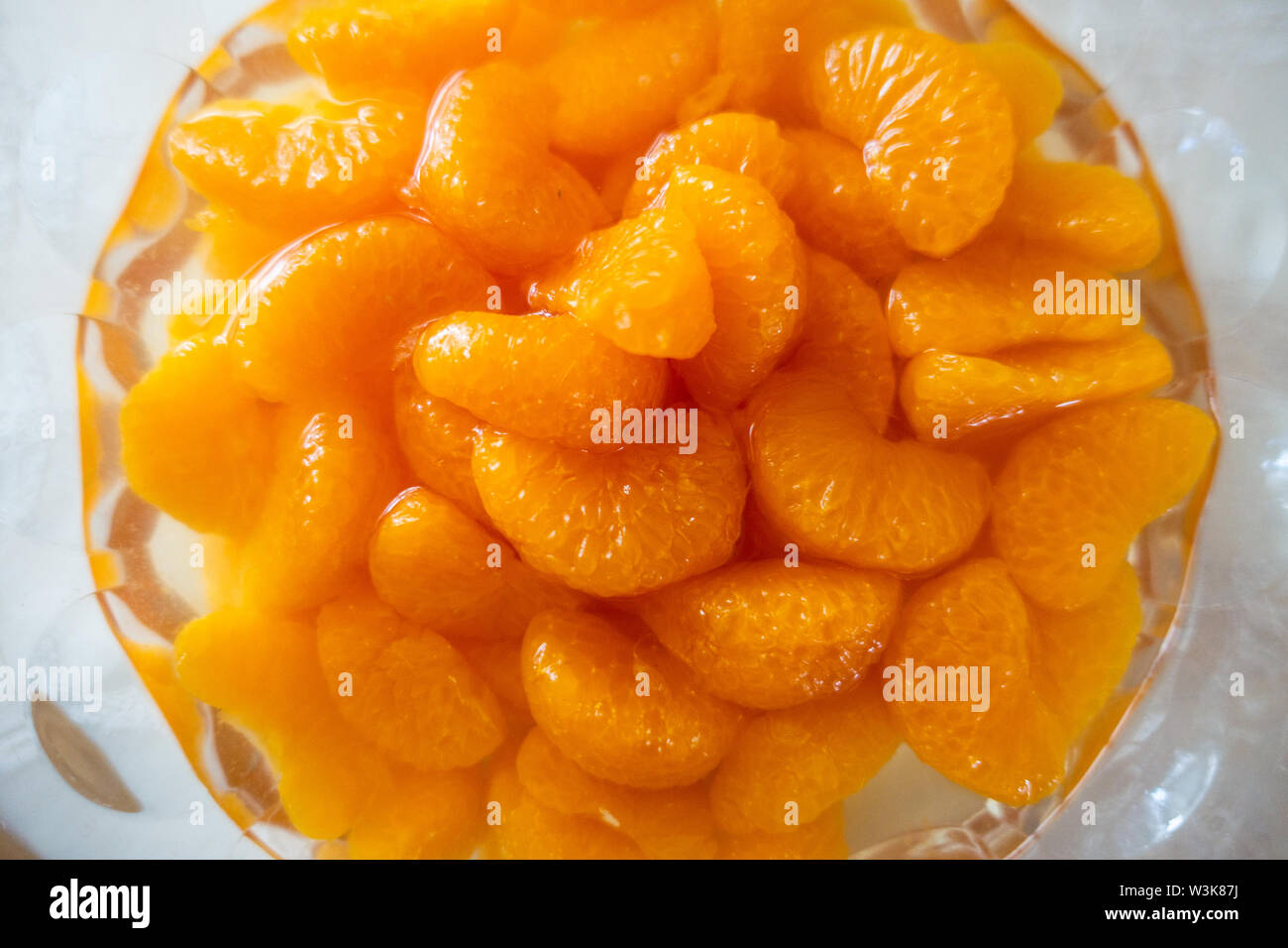 Looking down at mandarin orange slices from a tin served in a glass bowl. Stock Photo