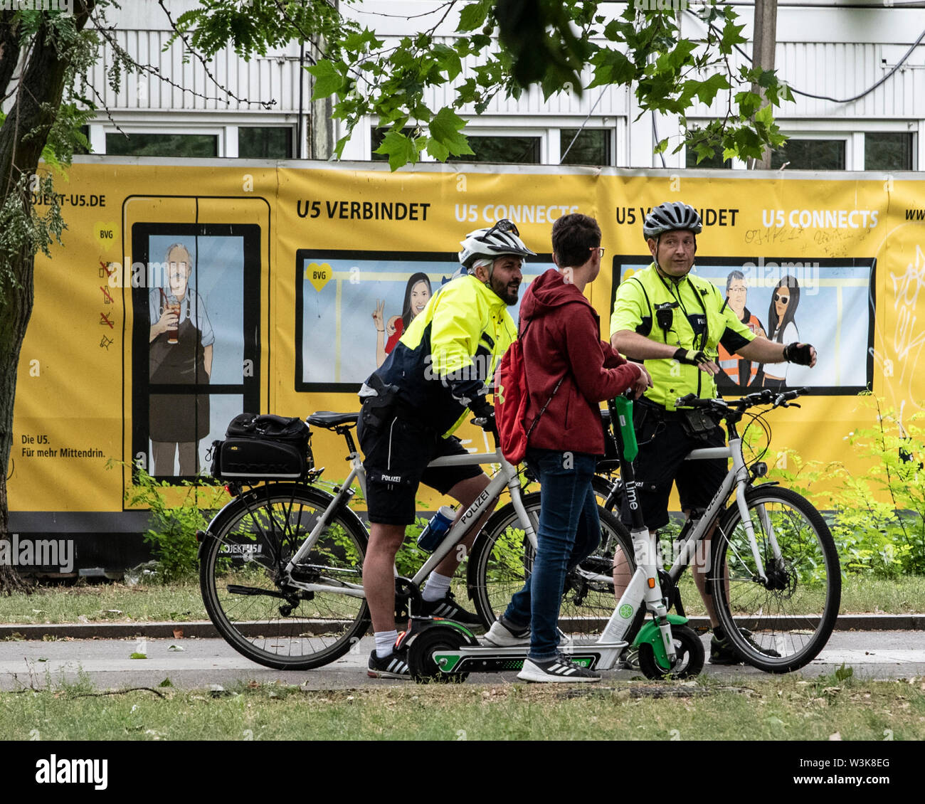 Berlin, Germany. 16th July, 2019. Bicycle squadron policemen check a young man with an electric pedal-scooter and point out misconduct in road traffic. Credit: Paul Zinken/dpa/Alamy Live News Stock Photo