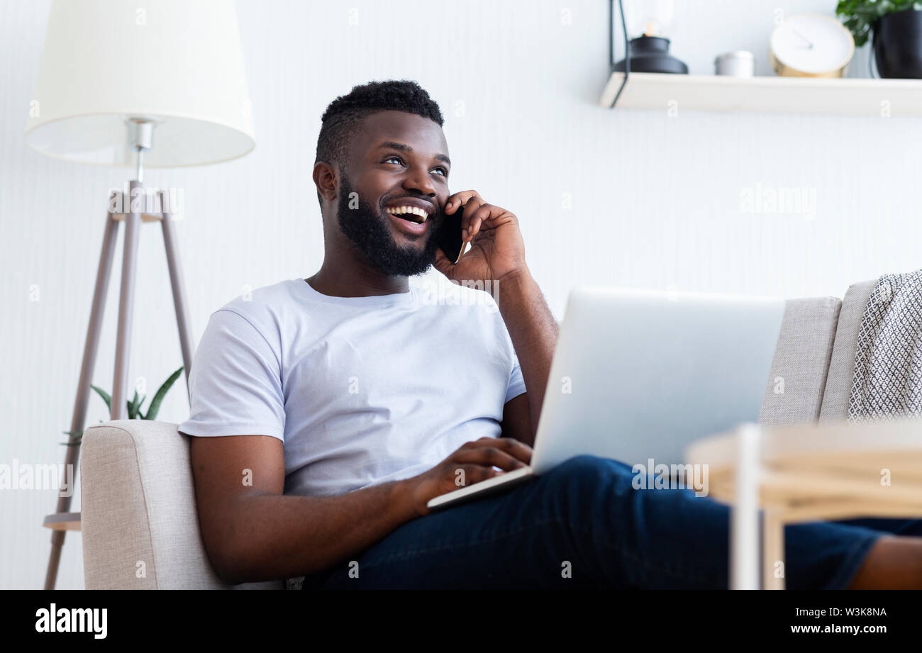 Young man talking on mobile phone and using laptop Stock Photo