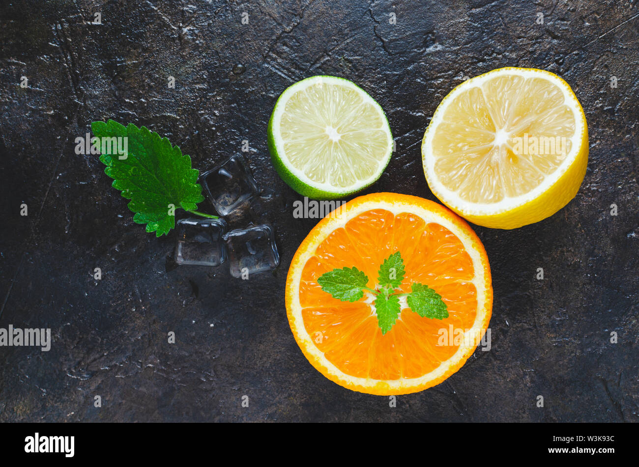 Slices of orange, lemon and lime with mint leaves on a concrete ...