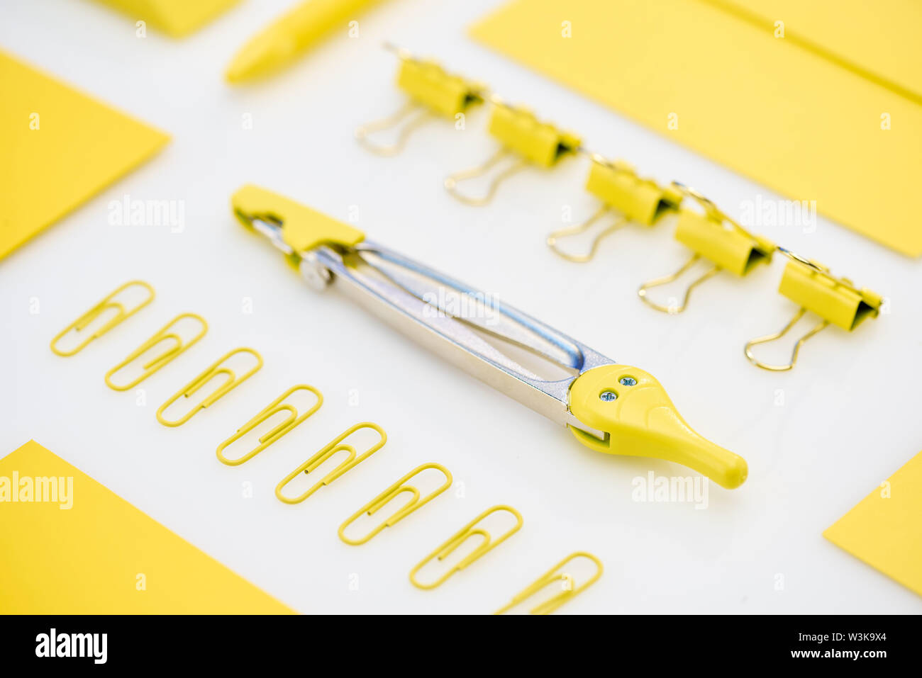 selective focus of yellow paper clips, compasses and envelope on white background Stock Photo