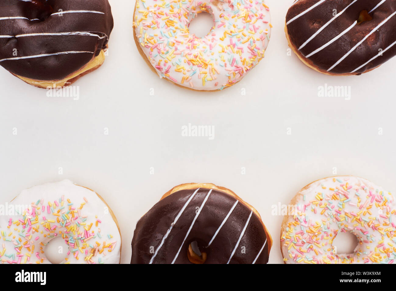 top view of chocolate glazed and white doughnuts with sprinkles on ...