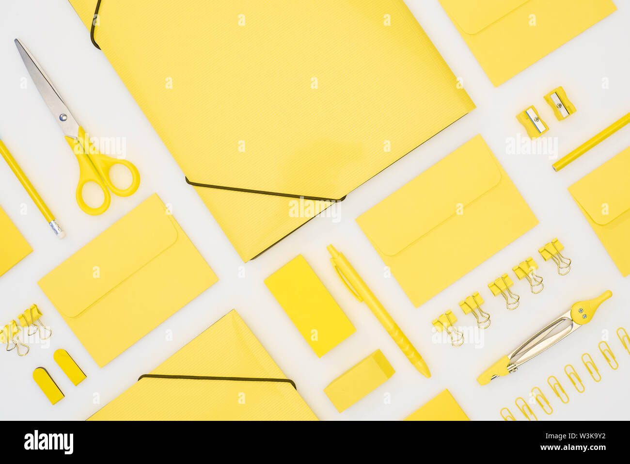 top view of yellow pen, pencils, paper clips, eraser, stickers, envelopes, stickers, folders, scissors, pencil sharpeners and compasses isolated on wh Stock Photo