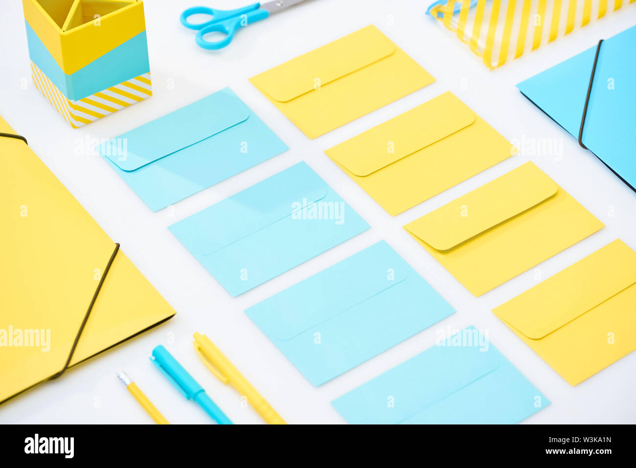 flat lay of blue and yellow envelopes and other stationery on white background Stock Photo