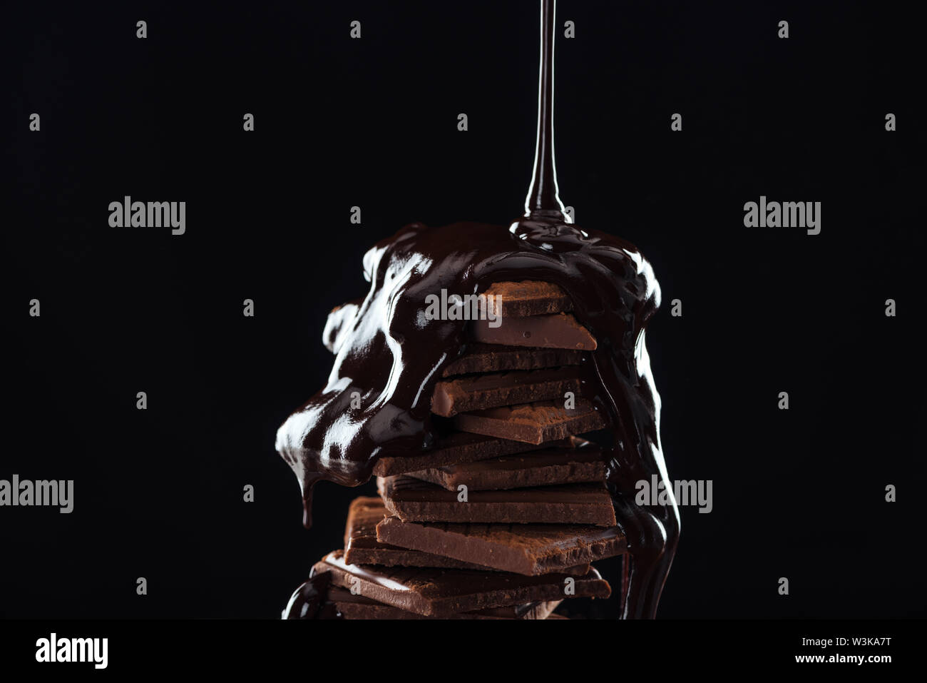 Hot melted chocolate pouring on chocolate stack, isolated on black ...