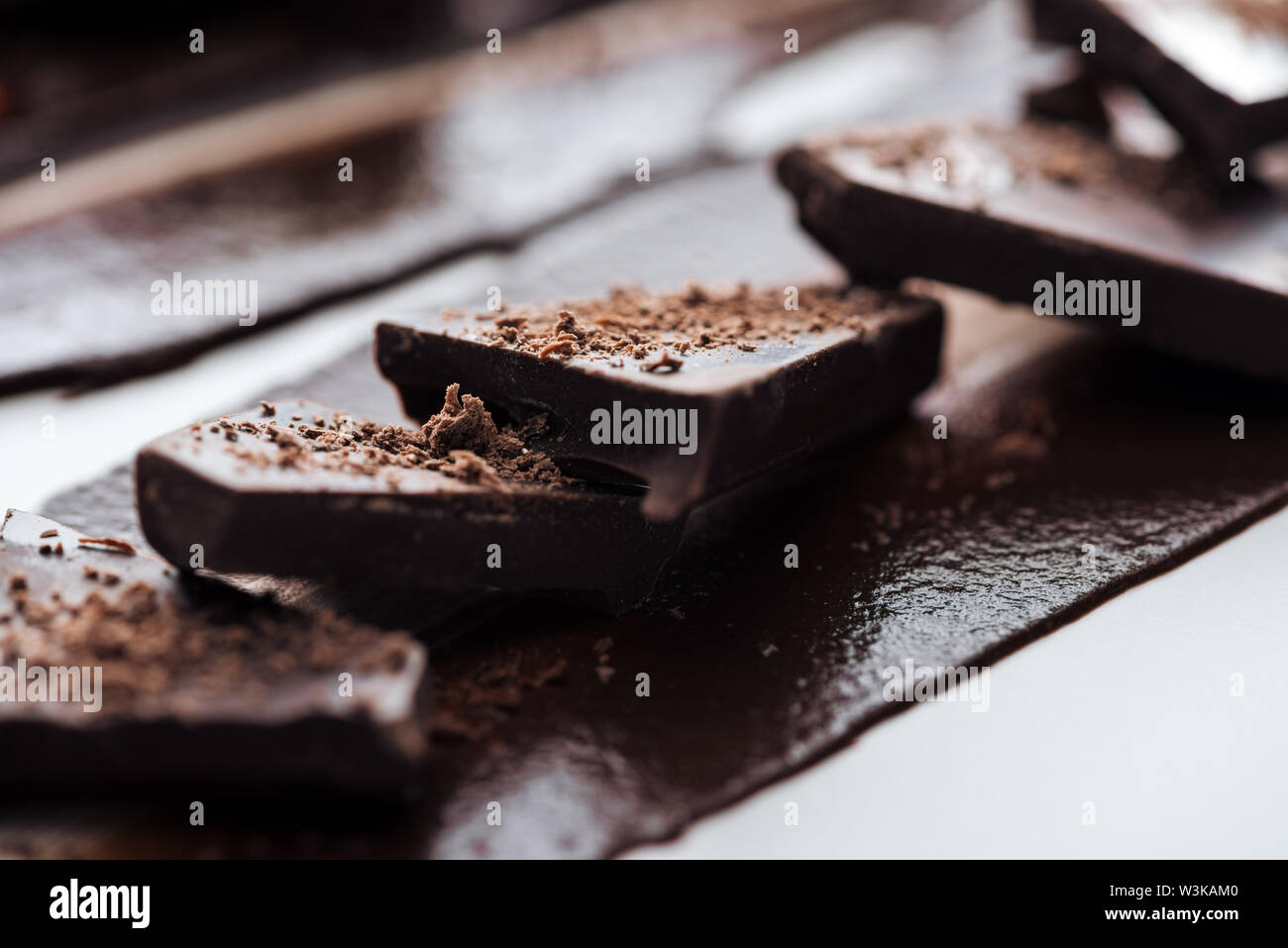 Selective focus of pieces of chocolate bar with cocoa powder and melted chocolate Stock Photo