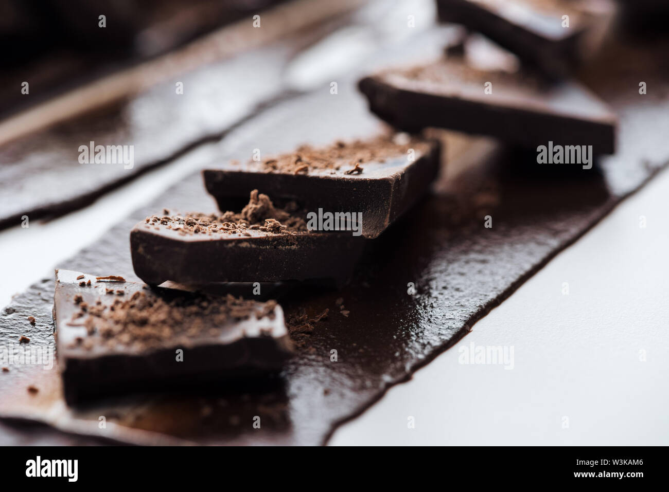 Selective focus of pieces of chocolate bar with cocoa powder Stock Photo