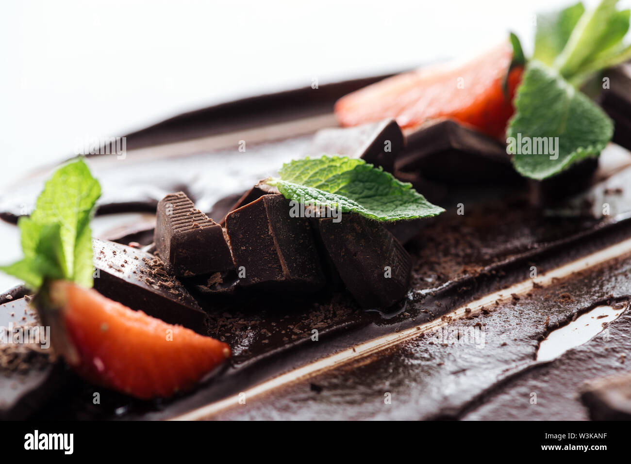 Close up view of pieces of chocolate bar, strawberries and fresh mint Stock Photo