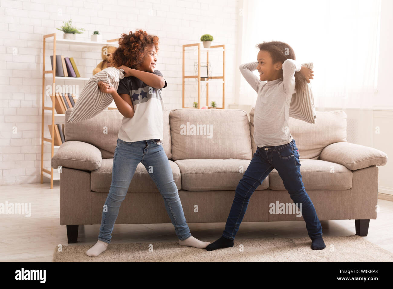African-american girls having fun, fighting with pillows Stock Photo