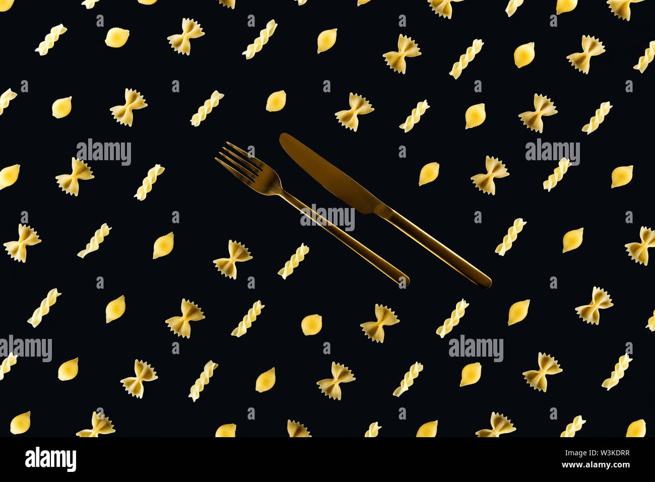 flat lay of different kinds of pasta with metal cutlery in middle ...