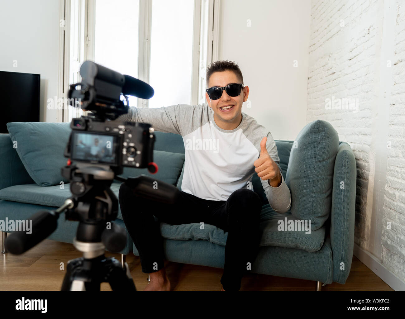 Happy trendy caucasian male on his twenties filming video blog on camera with tripod for online followers at home. In social media, Influencer, new te Stock Photo