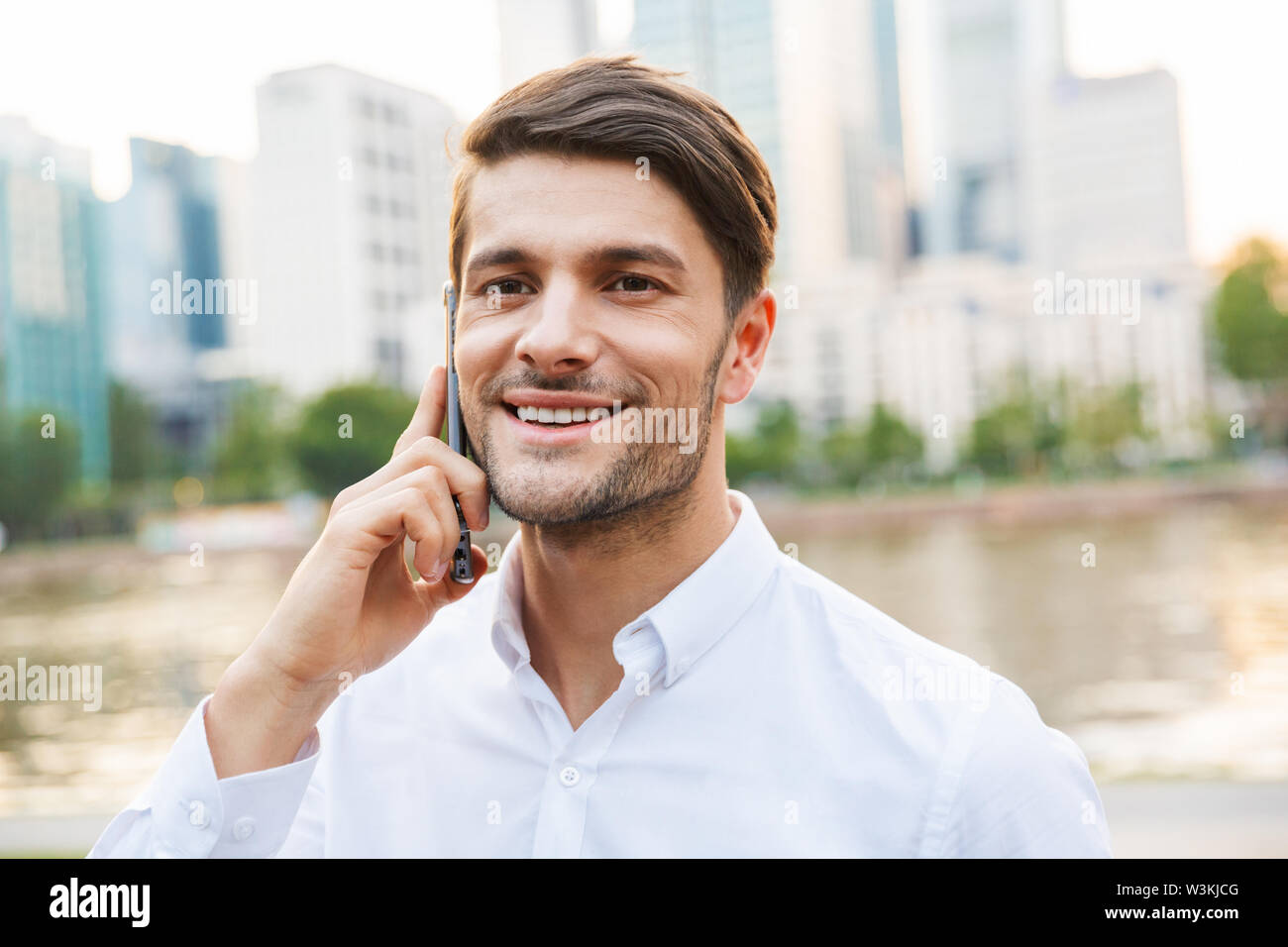 Photo of a young happy smiling handsome businessman standing outdoors ...