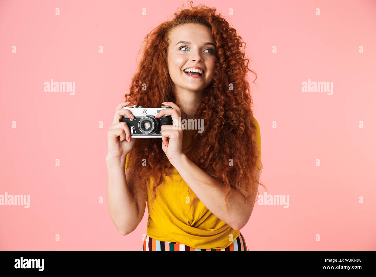 Portrait of an attractive cheerful young woman with long curly red hair ...