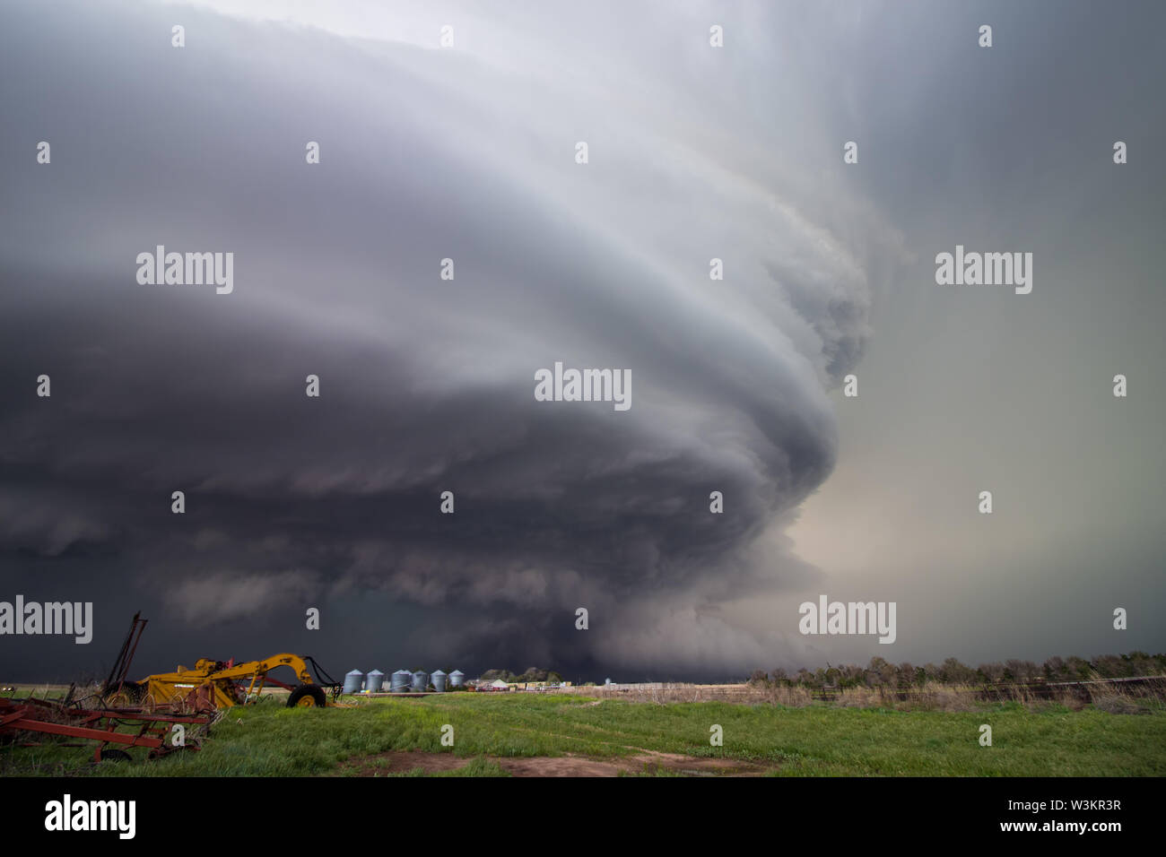 A huge supercell storm with a ground scraping wall cloud fills the sky over Nebraska farmland. Stock Photo