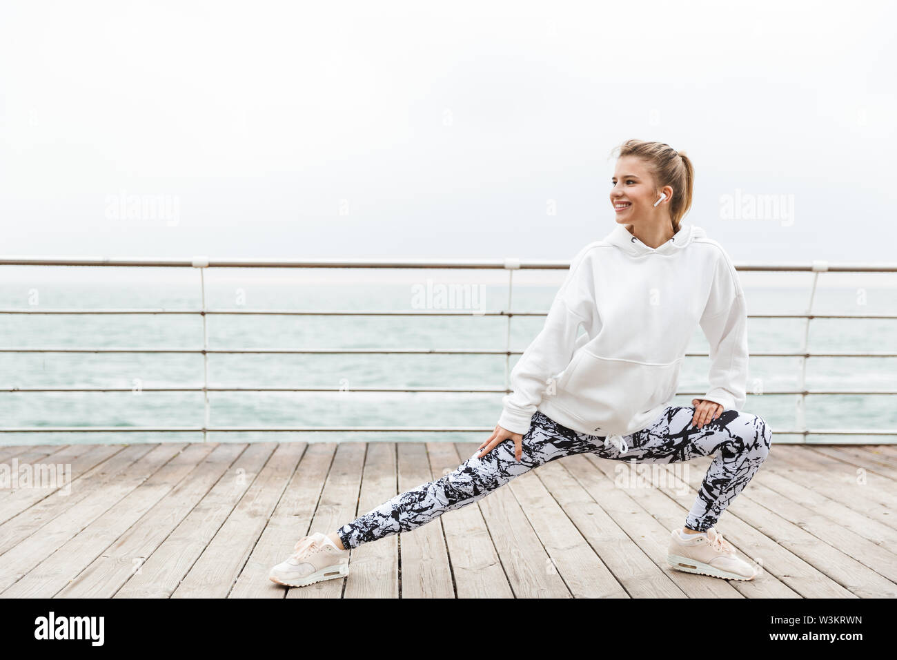 Attractive smiling young sportswoman wearing hoodie working out