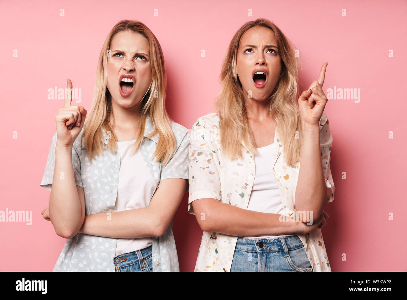 Picture of displeased shocked pretty blondes women friends posing isolated over pink wall background showing stop gesture. Stock Photo