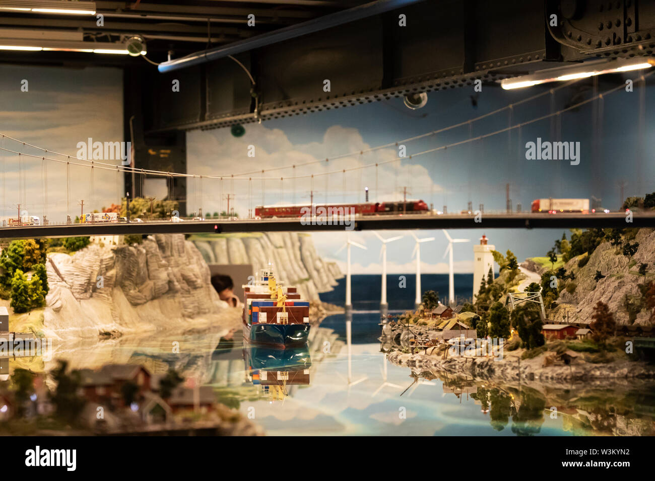 A model train crosses an elevated bridge past a container ship and wind turbines at the Miniatur Wunderland exhibit in Hamburg, Germany. Stock Photo
