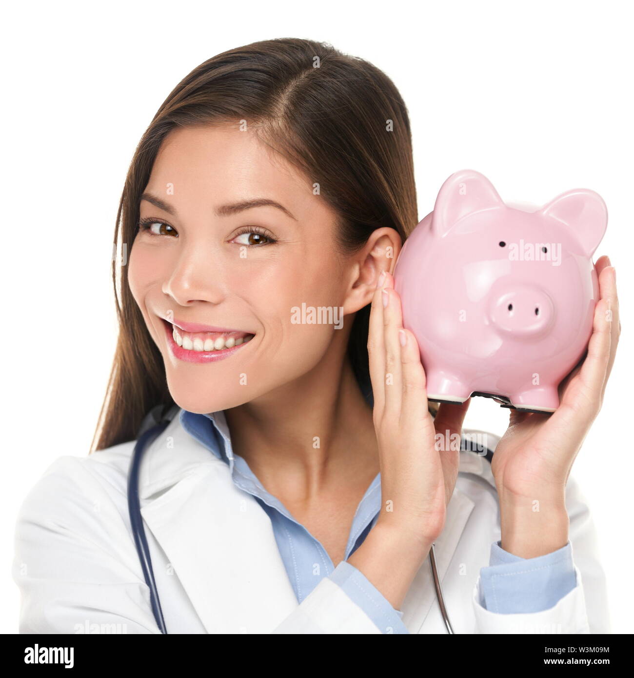 Healthcare concept - doctor holding piggy bank. Health care concept. Medical insurance or similar. Happy doctor woman shaking piggy bank looking smiling. Nurse or physician money concept isolated. Stock Photo
