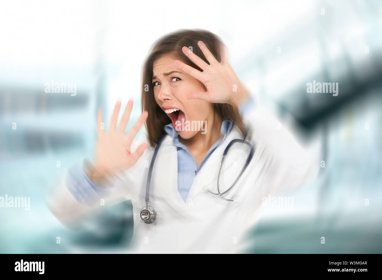 Surprised shocked scared doctor woman afraid and frightened covering her face with hands showing funny expression shocked and surprised. Female medical health care professional in hospital. Stock Photo