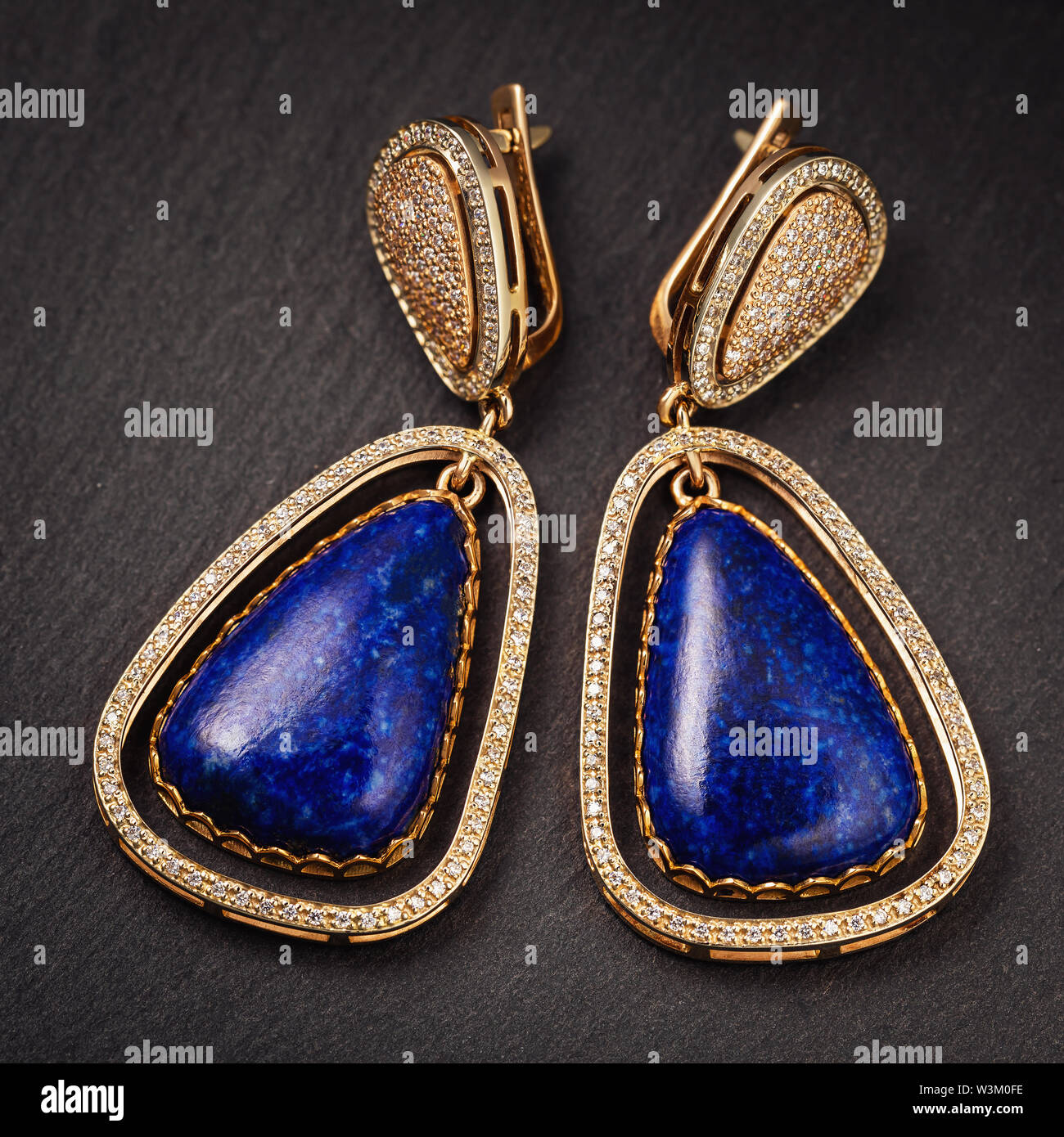 Beautiful gold earrings with lapis lazuli and small cubic zirconias, close-up Stock Photo