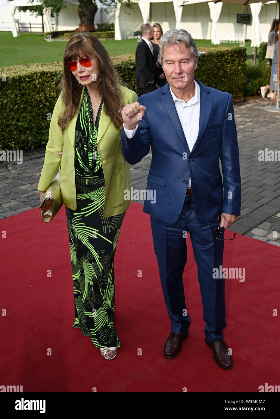 Cologne, Germany. 16th July, 2019. The actor John Savage (r) and her companion come to the MediaNight at the CHIO equestrian tournament. Credit: Henning Kaiser/dpa/Alamy Live News Stock Photo