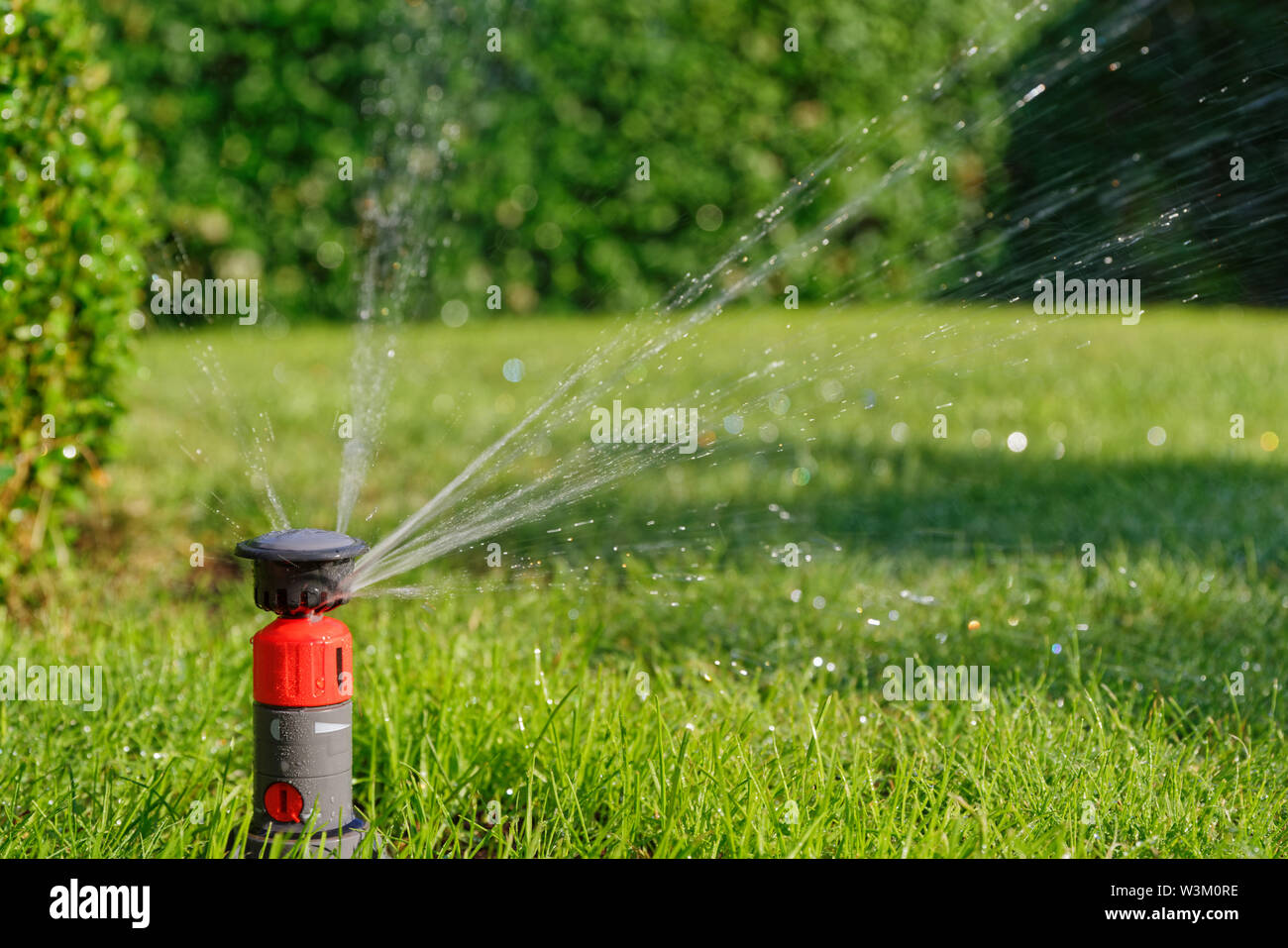 Orange automatic sprinkler in a garden while irrigation Stock Photo Alamy