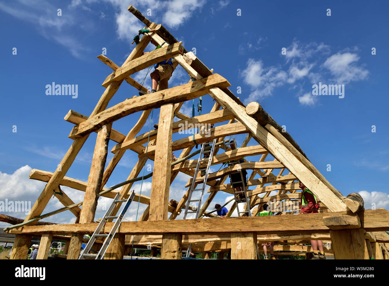 Carpenters working on roof of construction of new build traditional medieval Anglo Saxon timber framed building Stock Photo