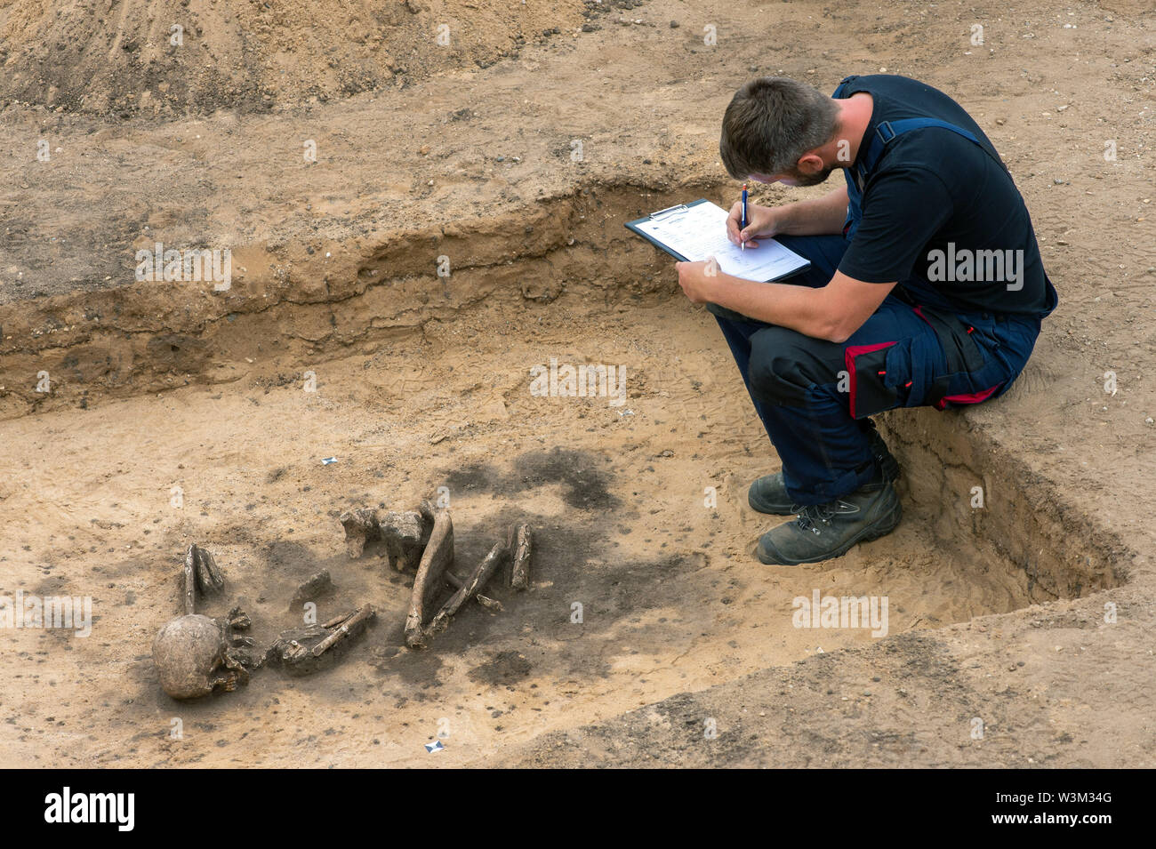 11 July 2019, Saxony-Anhalt, Pömmelte: The archaeologist Tim Grüne documents a grave from the Early Bronze Age in which the skeleton of a human being lies. The archaeologists date the stool burial to the years 2200 before Christ to 1900 before Christ. The bones are aligned in a north-south direction. The look of the skull goes east. During his lifetime man belonged to the Aunjetitz culture. Photo: Klaus-Dietmar Gabbert/dpa-Zentralbild/ZB Stock Photo
