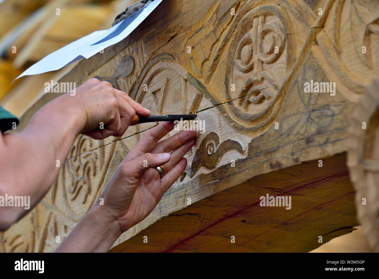 Carving motif into oak beam on traditional reconstruction of medieval timber framed hall Stock Photo