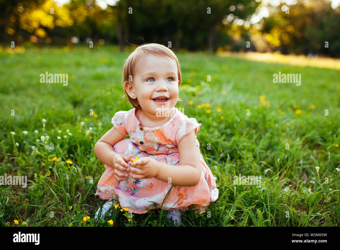 Little girl sitting on the grass in the park Stock Photo - Alamy