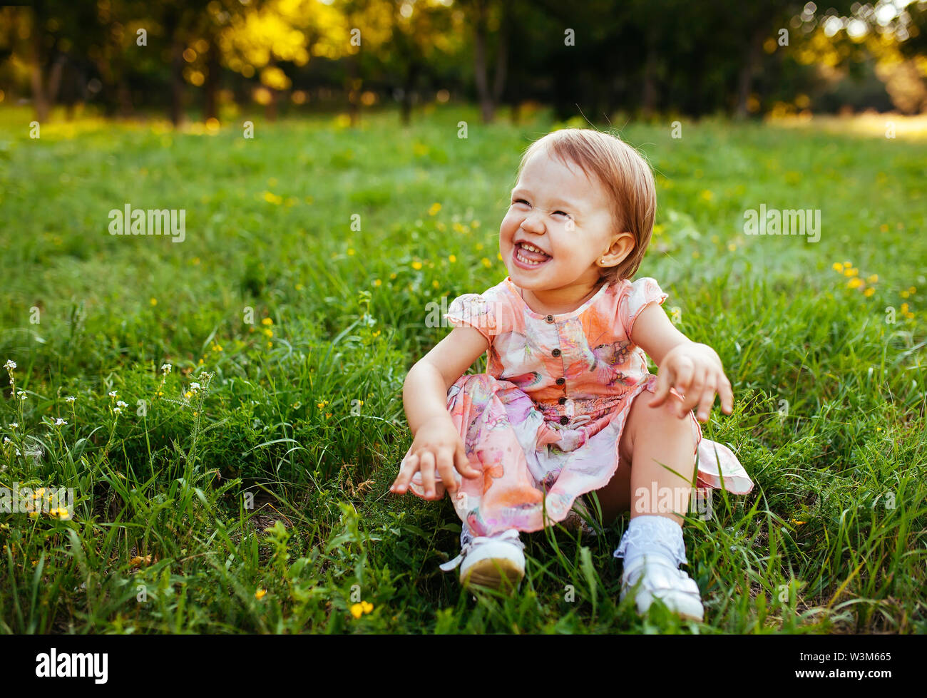 Little girl sitting on the grass in the park Stock Photo - Alamy