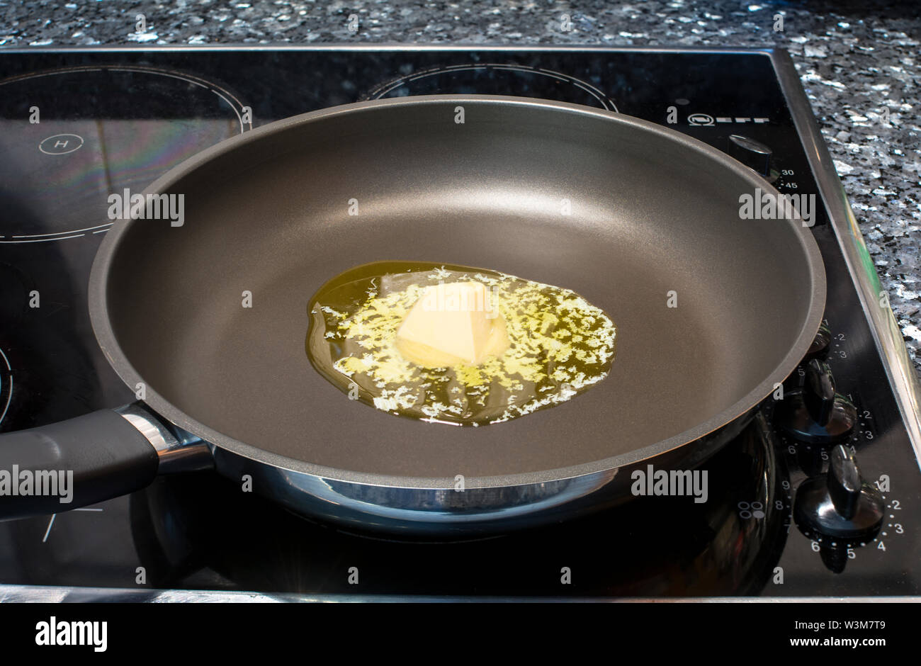Knob of butter melting on a frying pan Stock Photo
