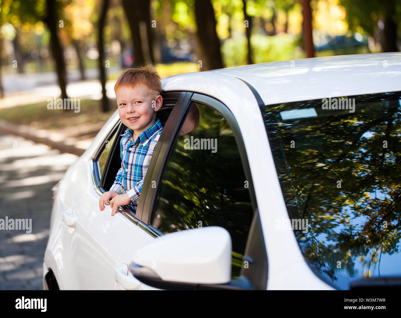 Adorable baby boy in the car. Laughing boy looks out of the car window. Stock Photo