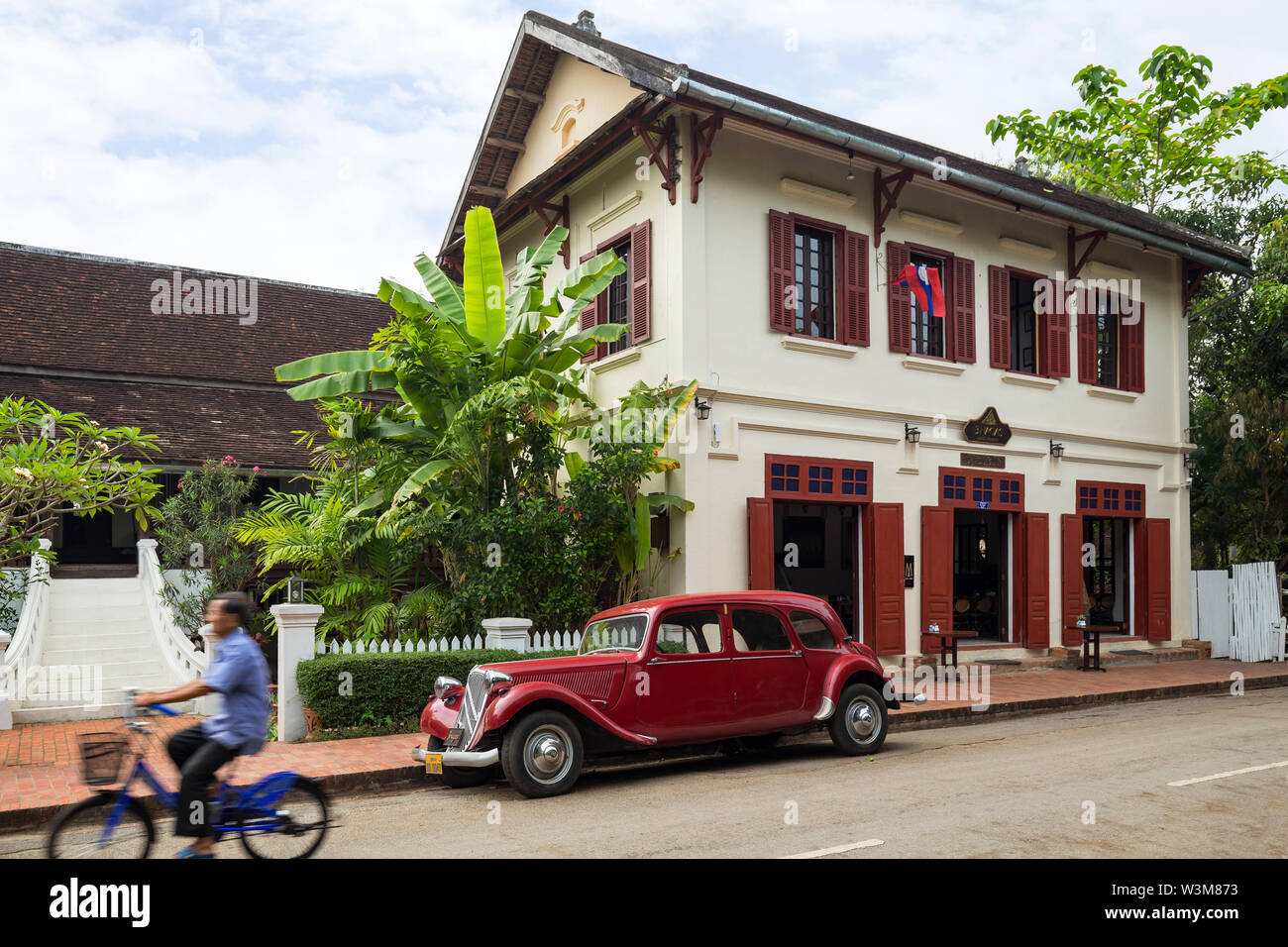 Old Citroen Traction Avant car parked in front of an old French colonial era building on the Sakkaline Road in Luang Prabang, Laos, in the morning. Stock Photo