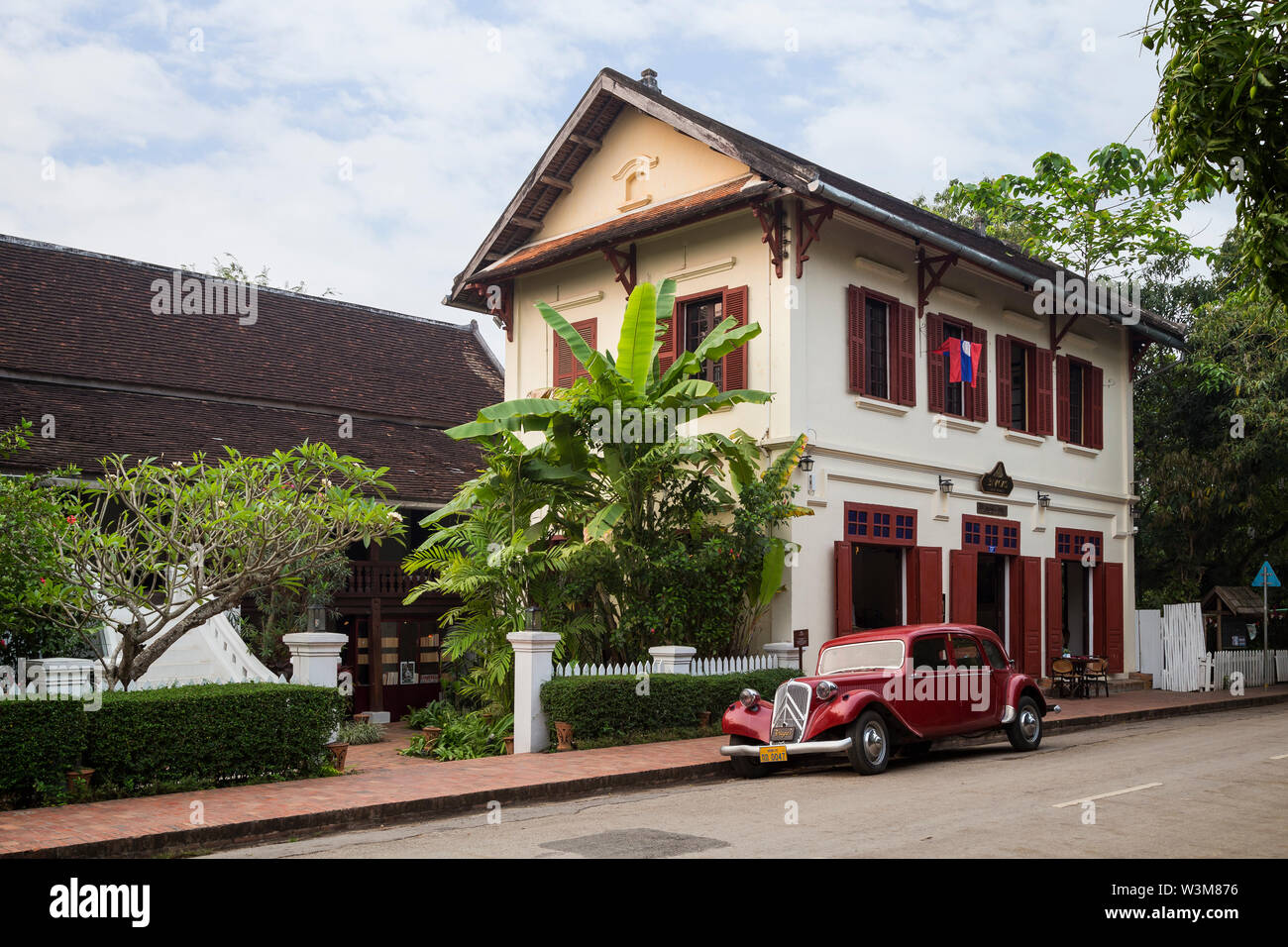 Old Citroen Traction Avant car parked in front of an old French colonial era building on the Sakkaline Road in Luang Prabang, Laos, in the morning. Stock Photo