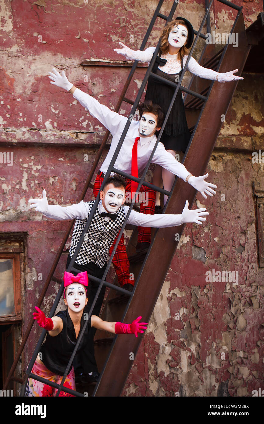 Four Mimes standing on the stairs on a red wall Stock Photo