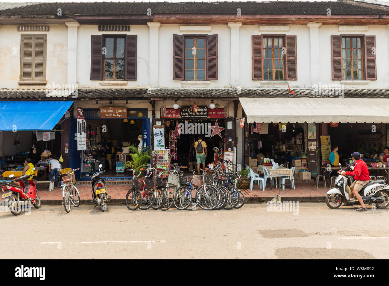 Bicycles and scooters parked in front of an old French colonial era building on the Sisavangvong Road in Luang Prabang, Laos. Stock Photo