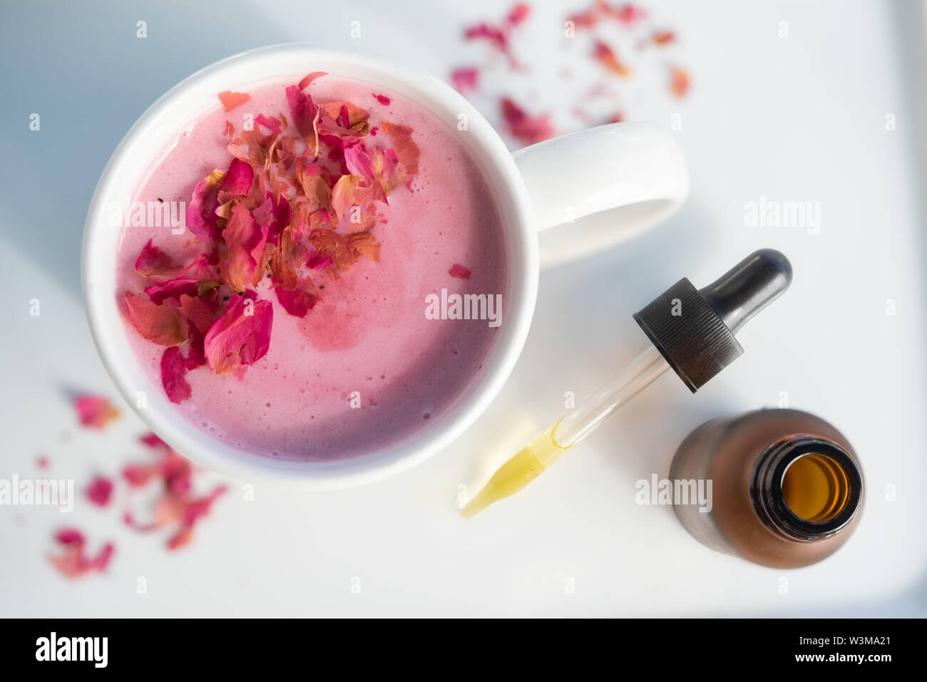 Pink drink topped with petals by pipette Stock Photo