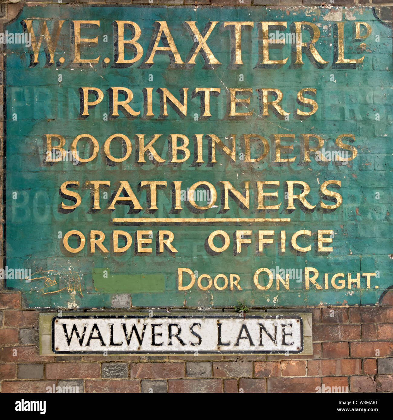 Old antique painted W.E. Baxter Ltd. Bookbinders and Stationers shop sign with faded gold lettering on brick wall Walwers Lane, Lewes, East Sussex, UK Stock Photo