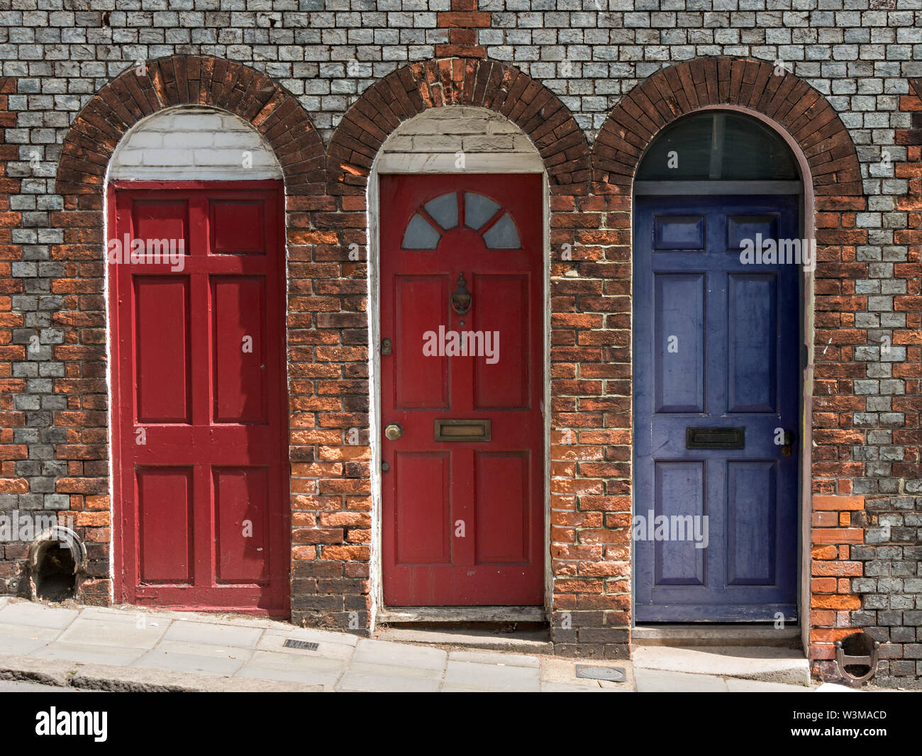 Three pretty terraced house wooden front doors set in arched brick doorways, Lewes, England, UK Stock Photo