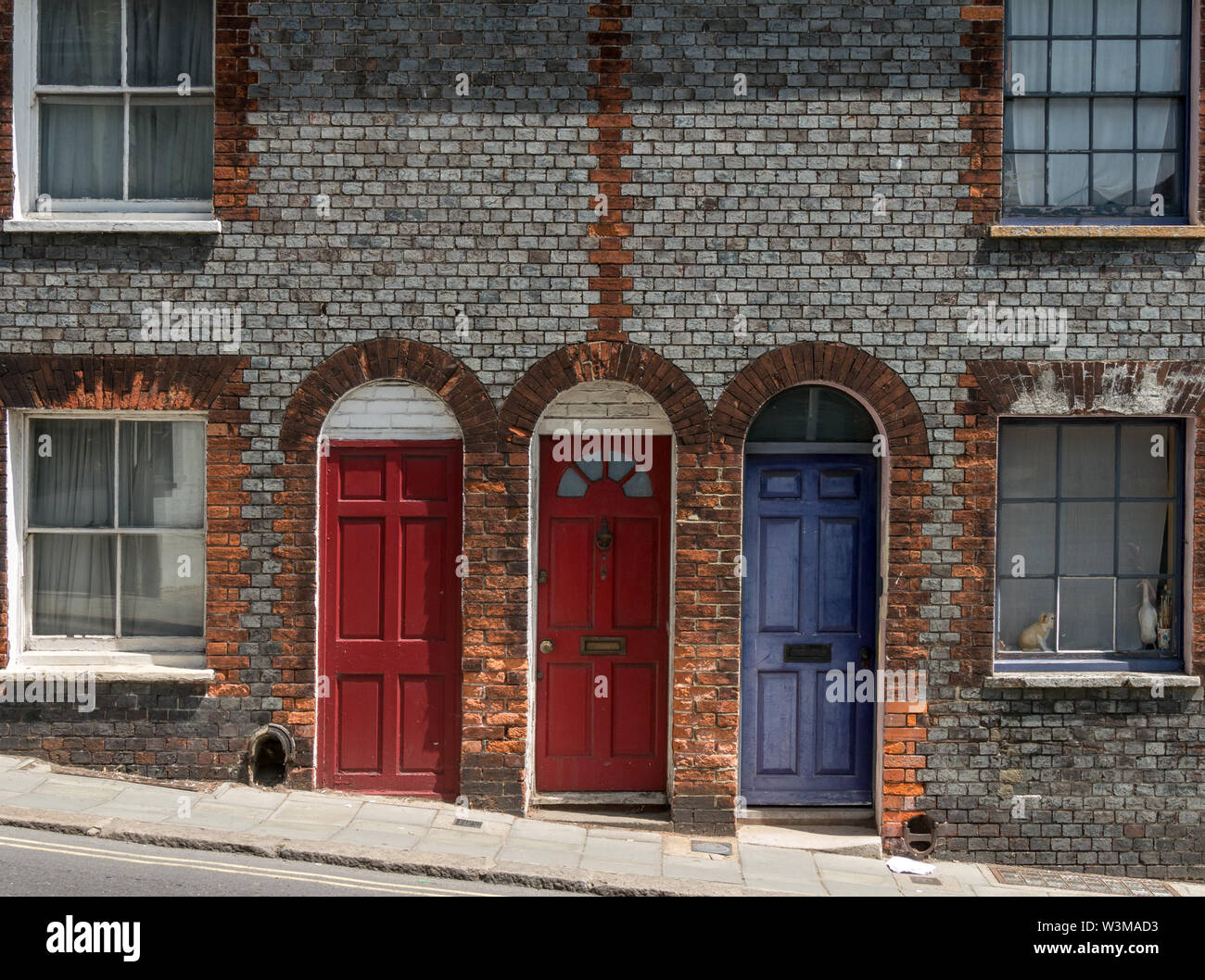 Three pretty terraced house wooden front doors set in arched brick doorways, Lewes, England, UK Stock Photo