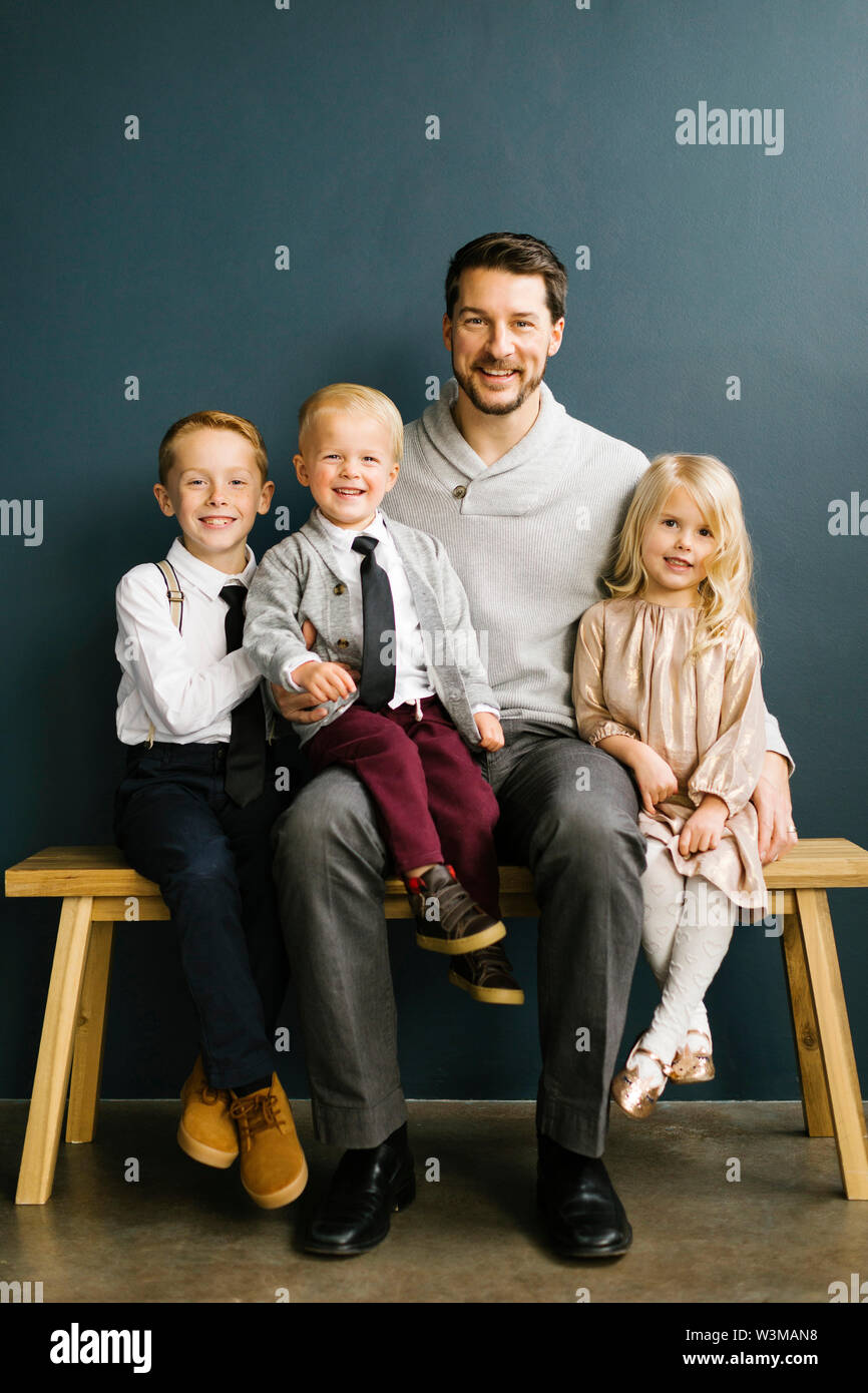 Father sitting with his three children Stock Photo
