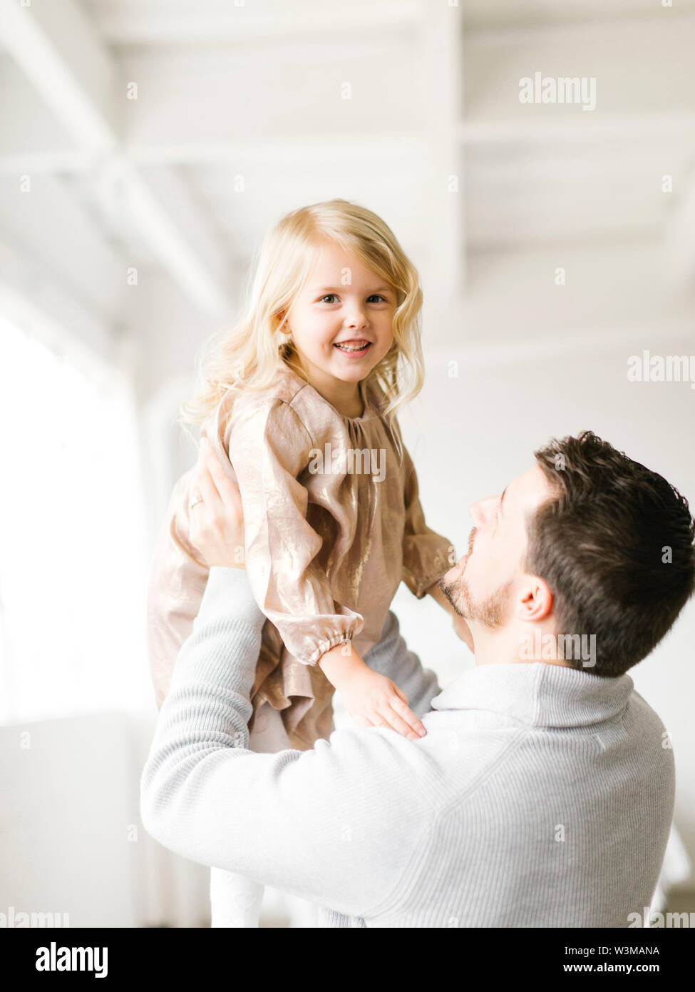 Mid adult man lifting his daughter Stock Photo