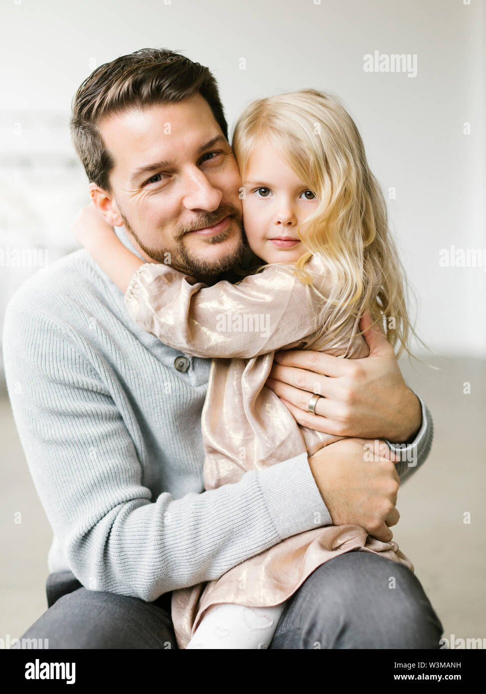 Girl sitting on her father's lap Stock Photo